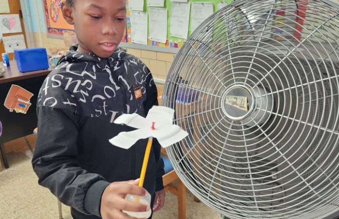  Student in front of fan showing the power of wind energy.